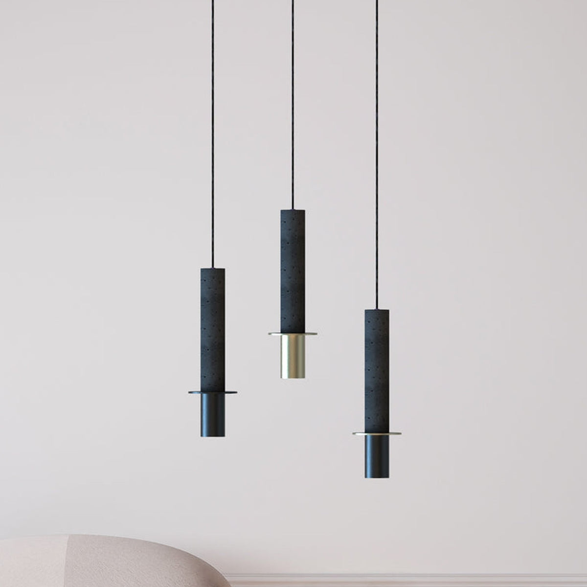 Rita Disc Pendant lights in dark grey textured concrete with matt polished brass base, shown as three staggered single-light fixtures in a living room setting.