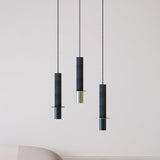 Rita Disc Pendant lights in dark grey textured concrete with matt polished brass base, shown as three staggered single-light fixtures in a living room setting.