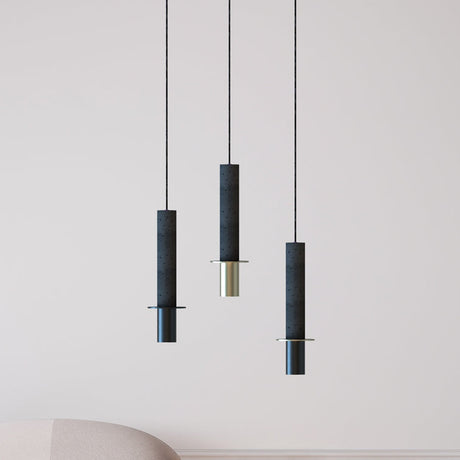 Rita Disc Pendant lights in dark grey textured concrete with matt polished brass base, shown as three staggered single-light fixtures in a living room setting.