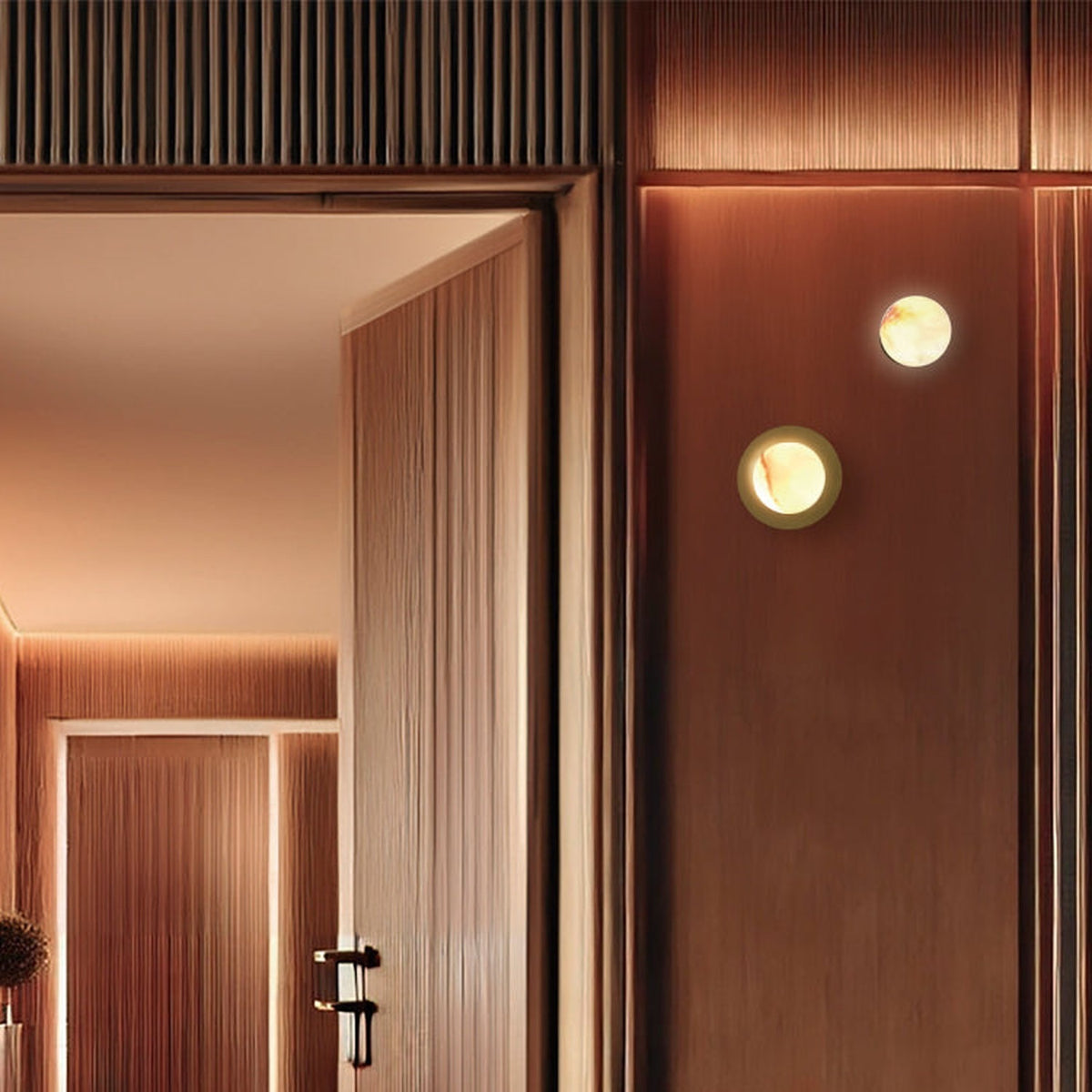 Royal Alabaster Globe Wall Light with Disc in matt polished brass, two fixtures lit on a wood-panelled wall beside a hallway doorway.