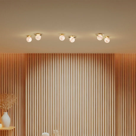 Royal Alabaster Flush Ceiling Lights with Disc in polished brass, shown in pairs along a wall-panelled room with warm, glowing globe shades.