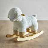 Laasrith Rocking Sheep in white, a curly fabric ride-on toy with sleepy embroidered eyes, floppy ears, wooden handle, and curved poplar wood rockers, shown on a wooden floor.