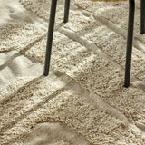 Elaine Wavy Cotton Rug in natural, 210x150cm, flatwoven with raised textured wave lines, shown underfoot beneath dark metal chair legs.