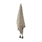 Charlie Cotton Throw in multicoloured fabric with a repeating sausage dog pattern, finished with green tassels, hanging against a plain white background.