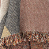 Close-up of the Arni Throw in Multi, showing woven colour-block panels in rust, grey, cream and gold with a thick mixed-yarn fringe edge.