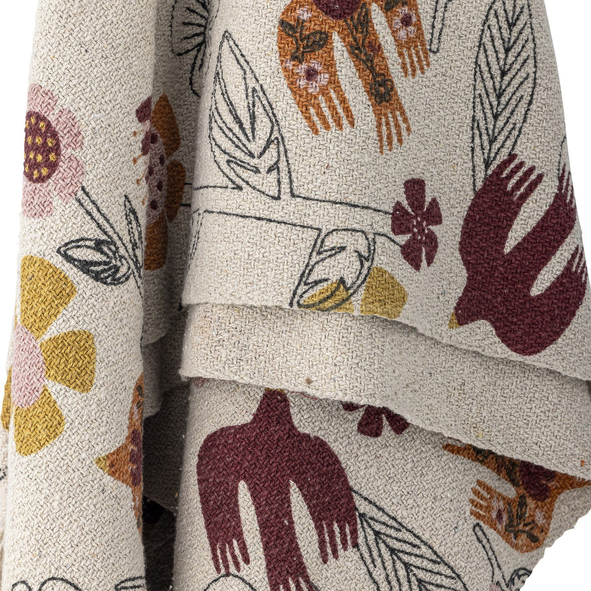 Vivielle Floral Throw in multicoloured fabric, draped in folds showing a textured weave printed with birds, flowers and line-drawn leaves.