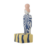 Priya Stoneware Tealight Holder in Multi: ceramic figure with pink bun and blue swirl-patterned body on a striped yellow and blue base, shown on white background.