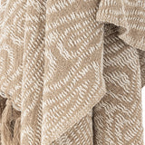 Okapi Cotton Throw in beige, draped in folds showing a woven wavy-line pattern in two tones with fringed tassel edge detail.