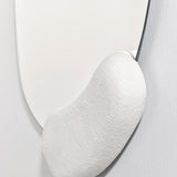 Close-up of the white form at the right, the plaster like finish meeting the mirror where the outline turns.