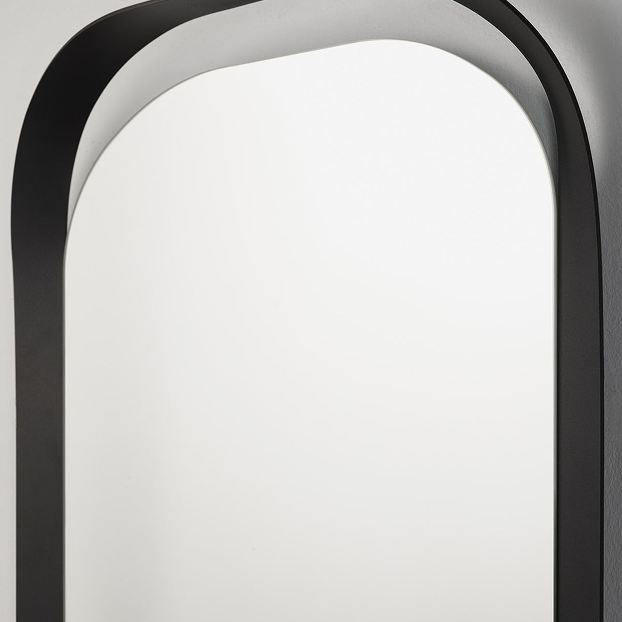Close-up of the rounded top of the frame, the black metal enclosing the oval glass in a single formed line.