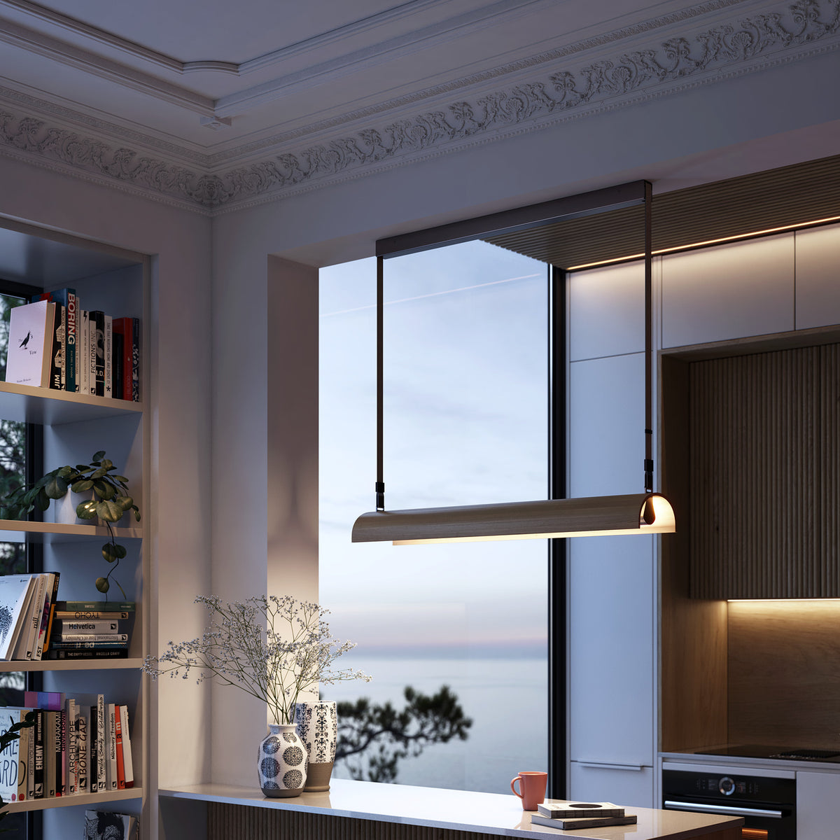Aluet S/100 LED pendant light with a half-round ash wood shade in beige, hung on cotton straps above a kitchen counter with a sea view through the window.