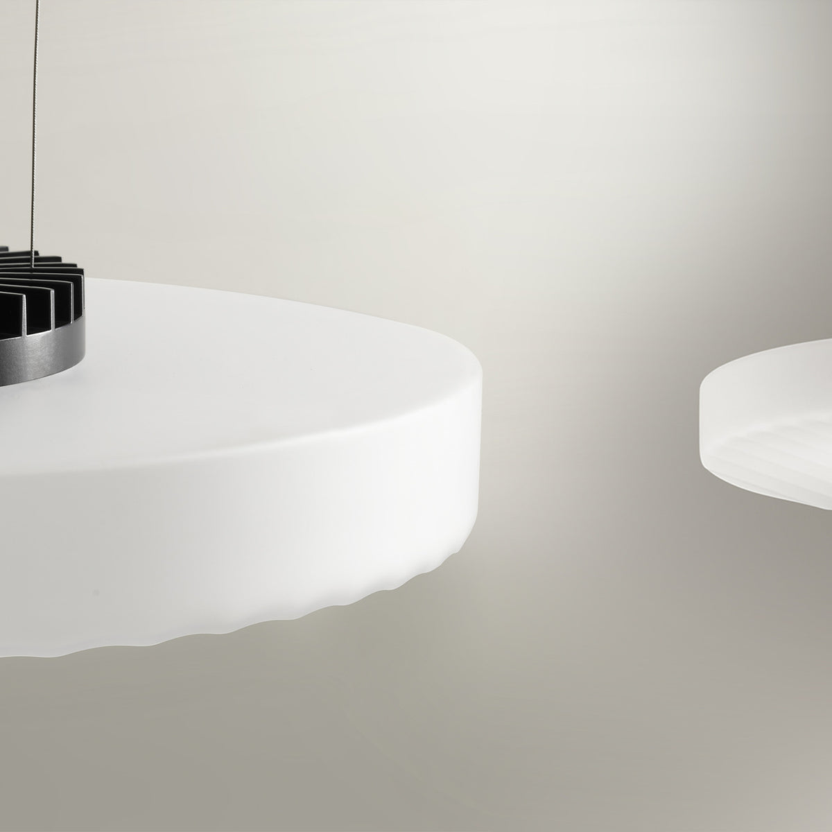 Côte Frosted White Glass LED Pendant Light shown close-up, a shallow ribbed disc shade with visible brushed metal LED fitting, against a plain light grey background.