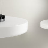Côte Frosted White Glass LED Pendant Light shown close-up, a shallow ribbed disc shade with visible brushed metal LED fitting, against a plain light grey background.