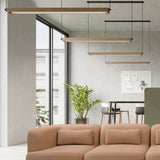 Roof S130 Casing linear pendant lights with wood-finish wrap shown in a modern living space above a tan sofa, alongside black-framed suspended fixtures.