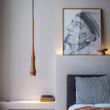 Slend 01 aluminium pendant light in terracotta, slim tapering form hanging beside a framed portrait sketch in a bedroom with striped pillows.