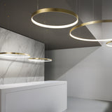 Zero Round Aluminium Ring LED Pendant Light in brushed brass, shown as multiple circular fixtures of varying sizes suspended above a marble-clad reception counter.