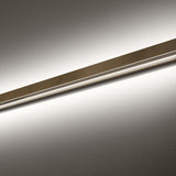 Close-up of the Zero Line Metal Linear LED Wall & Ceiling Light, a slim bronze bar with a recessed edge casting warm white light across a plain grey wall.