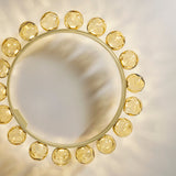 Murané R 18 ring chandelier, top view showing a brushed champagne band circled with textured amber glass spheres, illuminated against a plain light background.