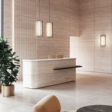 Roma Glass LED Pendant Light in Brushed Bronze with vertical bars and glowing white panels, shown as twin fixtures above a travertine reception desk.