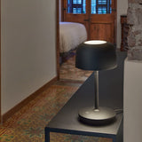 Bol M/37 Dome LED Table Lamp in matte black, rounded dome shade on a slim stem and round base, shown lit on a dark table in a hallway setting.