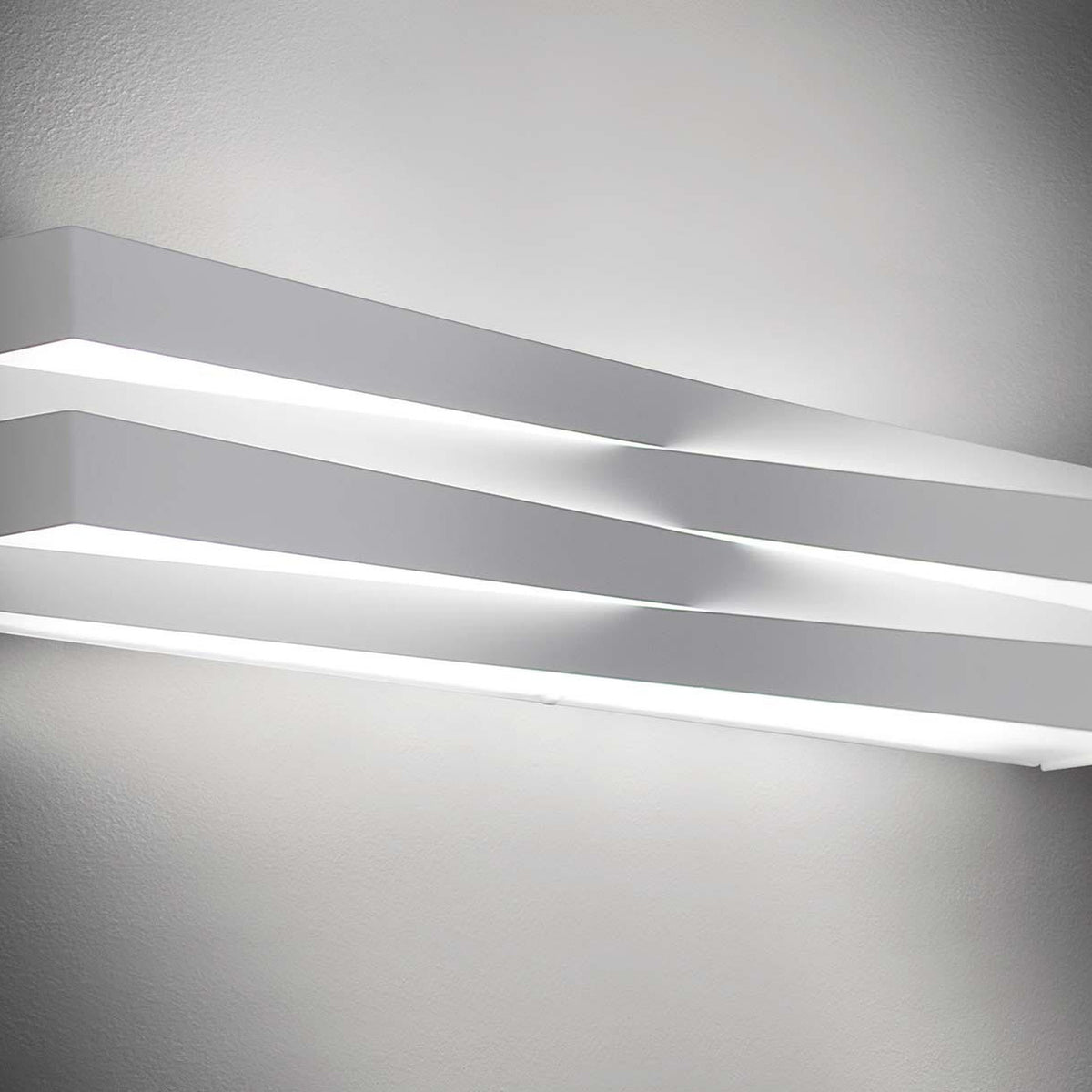 Cross Glass LED Wall Light 30cm in white finish, two crossing bars mounted on a light grey wall with warm white light glowing between them.