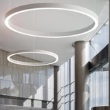 Golden Ring Aluminium LED Pendant Light in white, shown as two circular ring fixtures of different sizes suspended from a ceiling in a modern glass-walled interior.