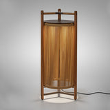 Kando P/111 outdoor floor lamp, a lit lantern-style cylinder of sand nautical cord within a teak wood frame, topped with a dark brown disc, on a plain grey background.