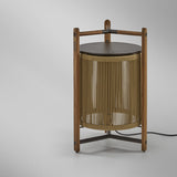 Kando P/76 outdoor floor lamp, lantern-style with sand nautical cord cylinder, teak wood tripod frame, wooden top handle and dark round lid, on a plain light background.