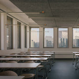 BIMU S100 Ele linear LED pendant lights, slim black bars with orange accent points, suspended from cables in a modern dining space with city-view windows.