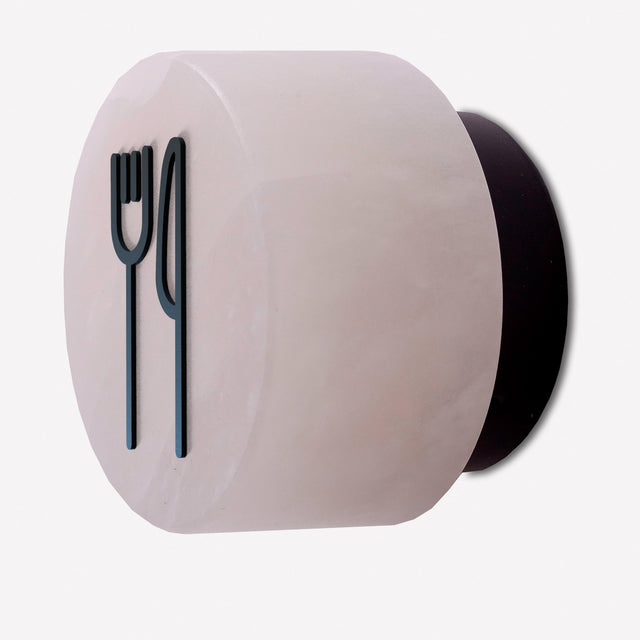 Rock wall light in alabaster with a matt black iron fork-and-knife signage symbol fitted to the front, shown on a plain white background.