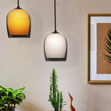 Bruma ribbed glass dome pendant lights in amber and oyster smoked glass, shown hanging above a plant-filled room with a framed picture on the wall.