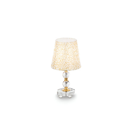 The Princess Small Crystal Table Lamp - Gold features an elegant floral-patterned, cream-colored shade. Its ornate, translucent base is highlighted by gold accents and crystal-like elements, set off beautifully against a refined gold metal frame on a pristine white background.