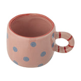 Nini Dotted Stoneware Cup in pink, a small 100ml child's cup with blue polka dots and a striped ring handle, shown on a plain white background.