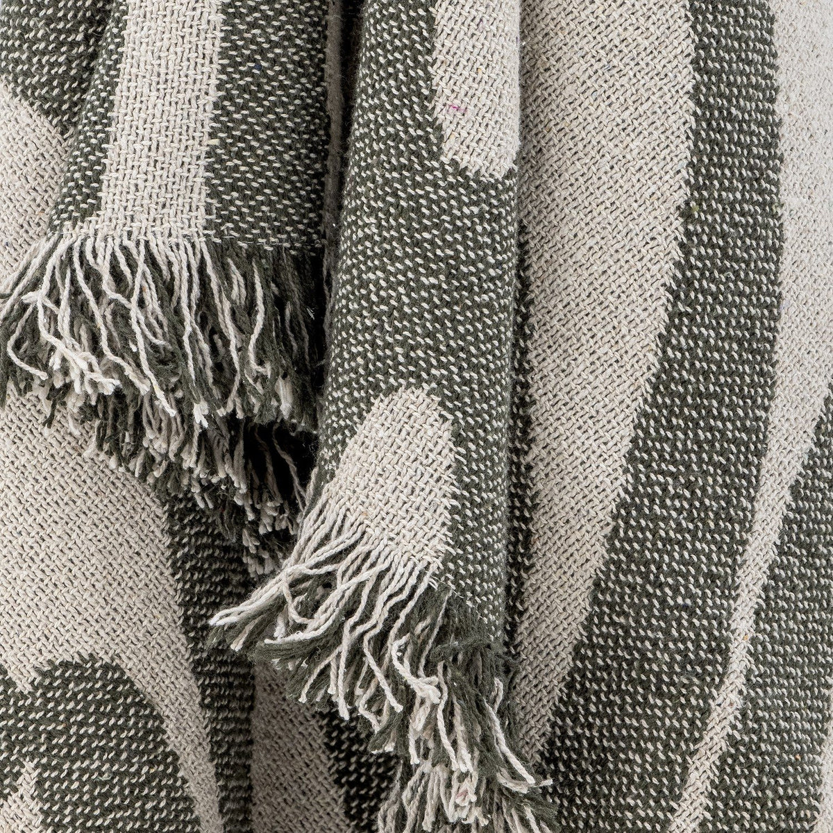Alk Cotton Throw in green, close-up of woven leaf-shaped pattern with loose fringed edge, showing textured cotton-blend yarn detail.