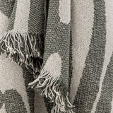 Alk Cotton Throw in green, close-up of woven leaf-shaped pattern with loose fringed edge, showing textured cotton-blend yarn detail.