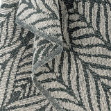 Ugento Leaf Cotton Throw in green, close-up of the woven fabric showing tall overlapping fern-leaf patterns in dark green on an off-white cotton blend.