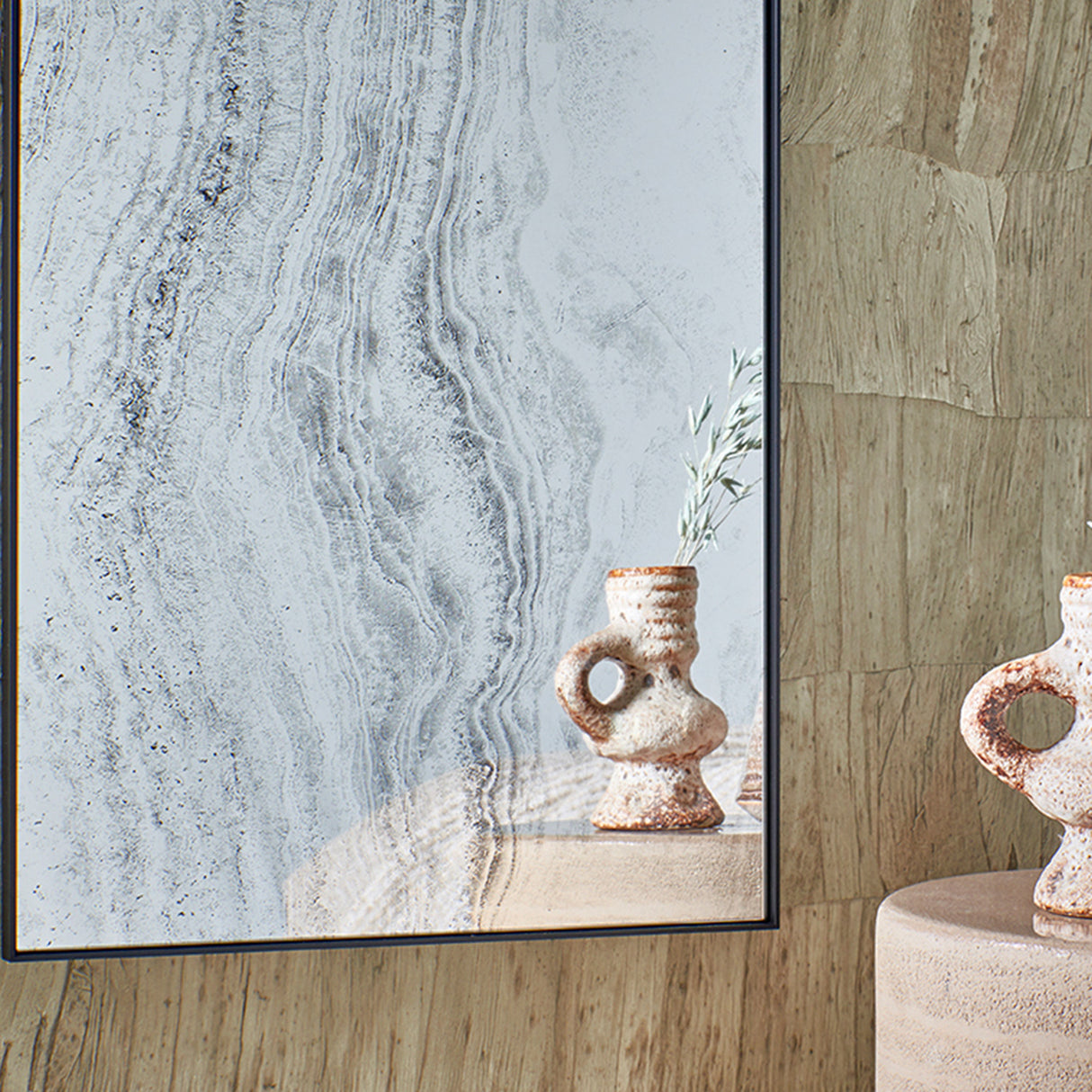 Close-up of the printed stone surface, ceramic vessels caught in the reflection where the pattern turns to clear mirror.