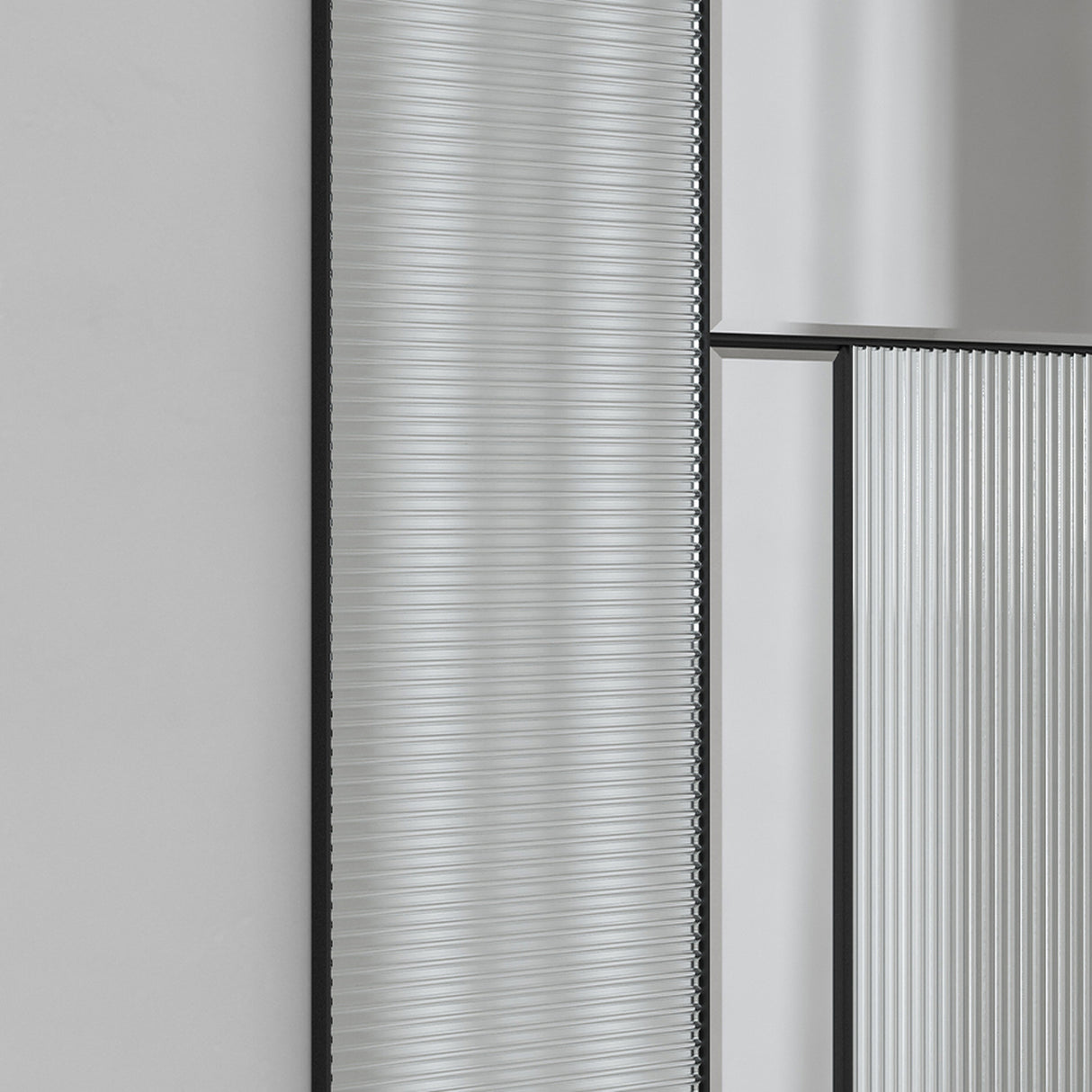 Close-up of the fluted glass ribs beside the plain mirrored panel, the two surfaces meeting on a black frame line.