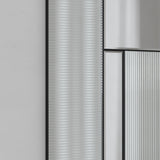 Close-up of the fluted glass ribs beside the plain mirrored panel, the two surfaces meeting on a black frame line.