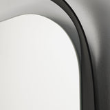 Close-up of the curved frame against the wall, showing the shadow the profile throws behind the oval glass.