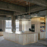 BIMU S150 Ele linear LED pendant light in black, hung on thin cables above a kitchen island in a concrete-ceilinged industrial interior.