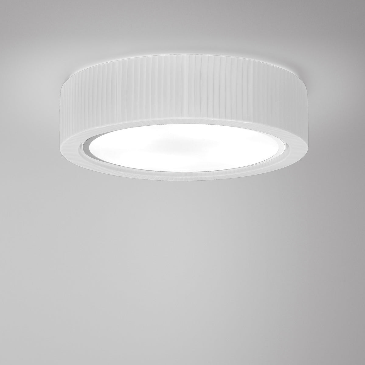Urban PF/60 Ribbon LED ceiling light, round drum shade in white translucent pleated ribbon with a broad white diffuser underside, set against a plain light grey background.