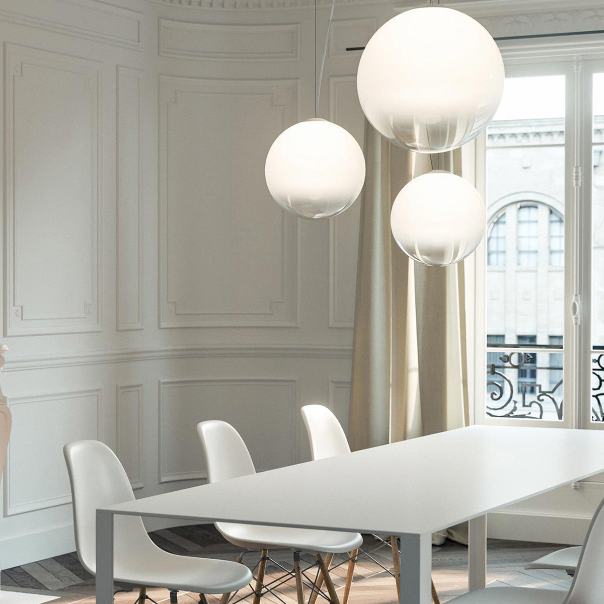 Smoke Glass Globe LED pendant lights in varying sizes hang above a white dining table with white chairs, set against panelled white walls.