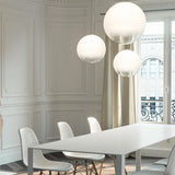 Smoke Glass Globe LED pendant lights in varying sizes hang above a white dining table with white chairs, set against panelled white walls.