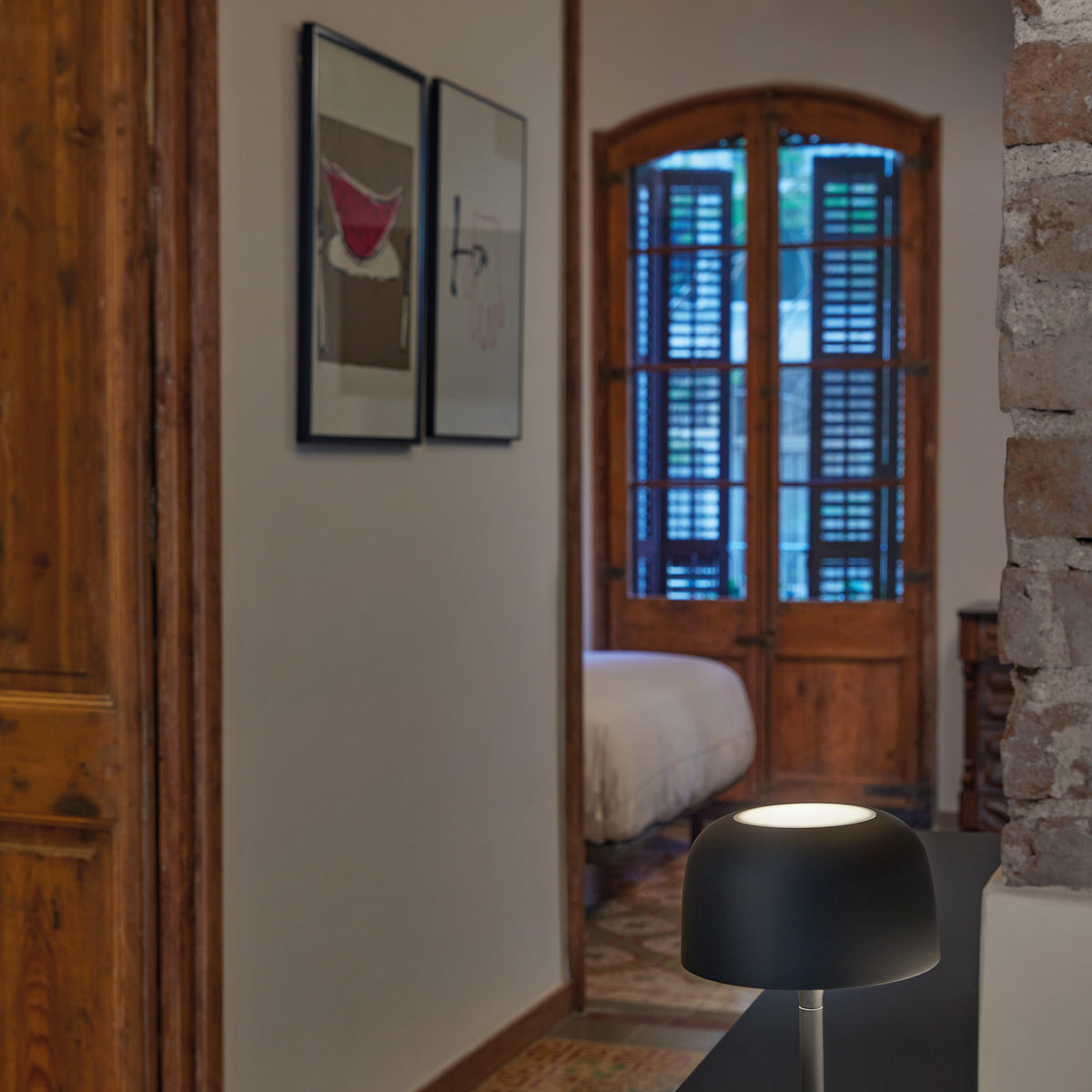 Bol M/37 Dome LED Table Lamp in matte black, with rounded dome shade on a slim stem and round base, shown on a console table in a hallway leading to a bedroom.