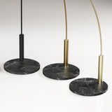 Dip Nero Marquina Arc LED Floor Lamp bases shown in black, brushed brass and champagne finishes on round Nero Marquina marble bases, set against a plain light background.