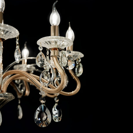Detailed view of the Prismara Crystal 10 Light Chandelier - Gold, featuring luminous candle-shaped bulbs, intricate glass droplets, and elegantly curved metal arms, all beautifully set against a dark background.