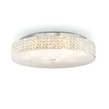 The Nebula 12 Light Crystal Ceiling Light in chrome showcases a sleek, round design with a frosted glass base, complemented by an elegant crystal-like band around the side. Its modern style adds sophistication while providing a soft and ambient glow.