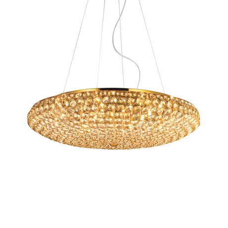 The Queen 12 Light Crystal Suspension - Gold is a decorative circular chandelier with a luxurious gold finish and adorned with numerous crystal embellishments. It hangs gracefully by thin wires and emits a warm glow, adding an elegantly luxurious touch to any interior.