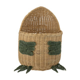 Eddi Dinosaur Rattan Basket in natural with green woven arm details and clawed feet, egg-shaped body and tall rounded head, shown on a plain white background.